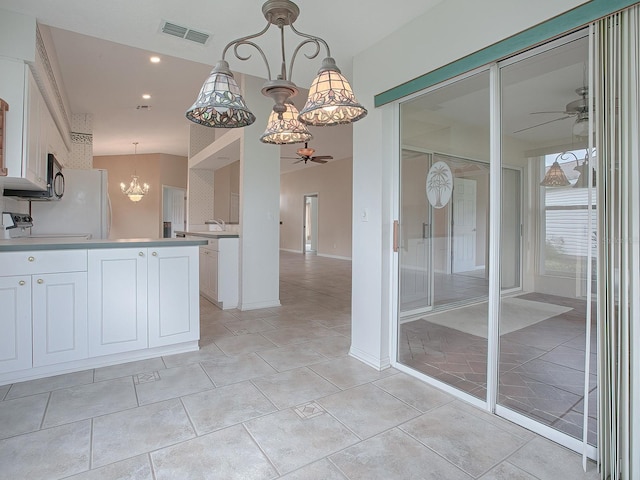 kitchen featuring decorative light fixtures, white cabinets, ceiling fan with notable chandelier, and range