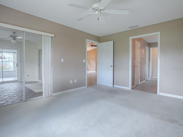 unfurnished bedroom featuring ceiling fan, a closet, and light colored carpet