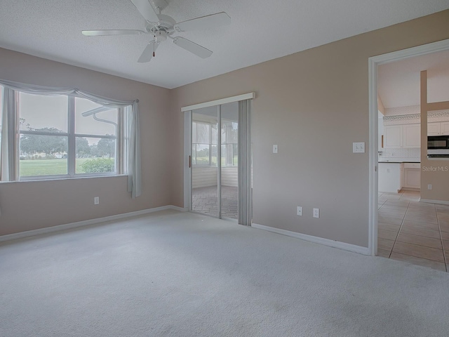 carpeted empty room with a textured ceiling, ceiling fan, and a healthy amount of sunlight