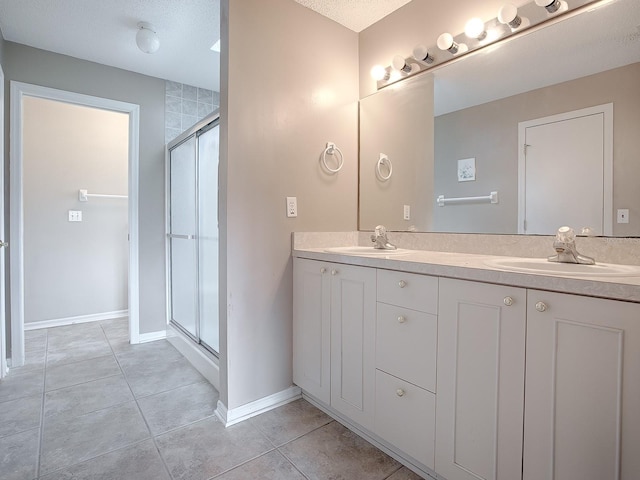 bathroom with tile patterned flooring, a textured ceiling, walk in shower, and vanity