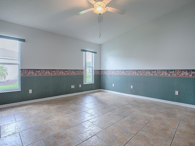 spare room featuring a textured ceiling, ceiling fan, and vaulted ceiling