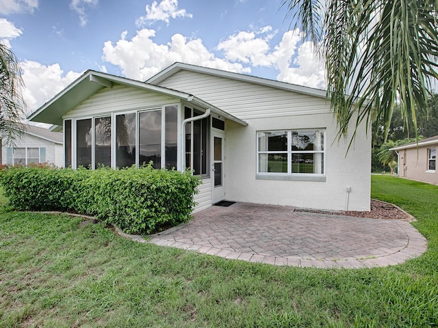 rear view of house featuring a yard, a patio, and a sunroom