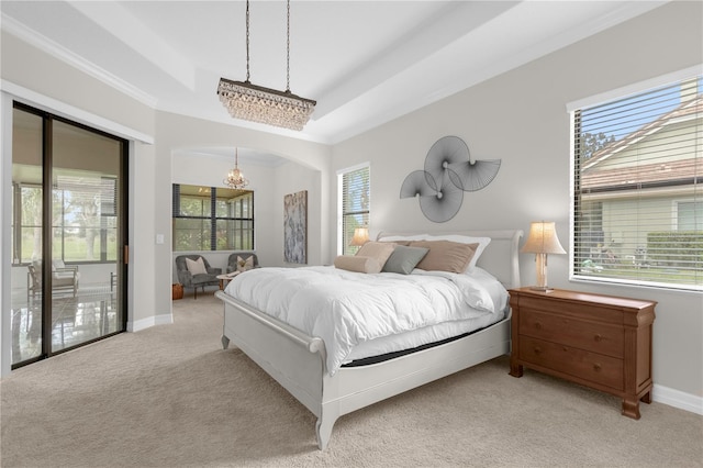 carpeted bedroom with an inviting chandelier, ornamental molding, and a raised ceiling