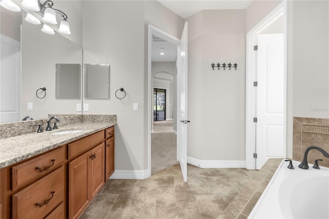 bathroom with a bathtub, vanity, and an inviting chandelier