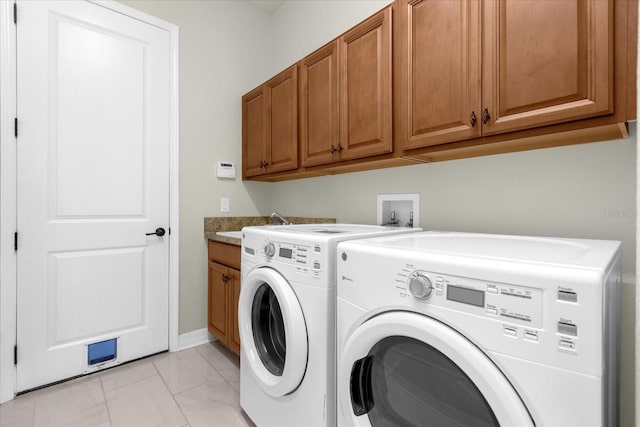 washroom featuring cabinets, light tile patterned flooring, and washing machine and clothes dryer