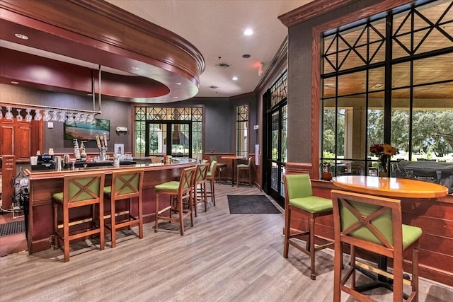 bar with crown molding and light wood-type flooring