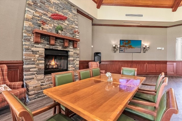 dining room featuring hardwood / wood-style floors, beam ceiling, and a stone fireplace