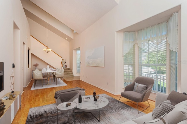 living room featuring light wood-type flooring, high vaulted ceiling, and a notable chandelier