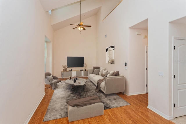 living room with ceiling fan, high vaulted ceiling, and light wood-type flooring