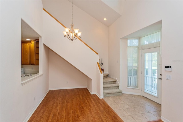 entrance foyer with high vaulted ceiling, a notable chandelier, and light wood-type flooring