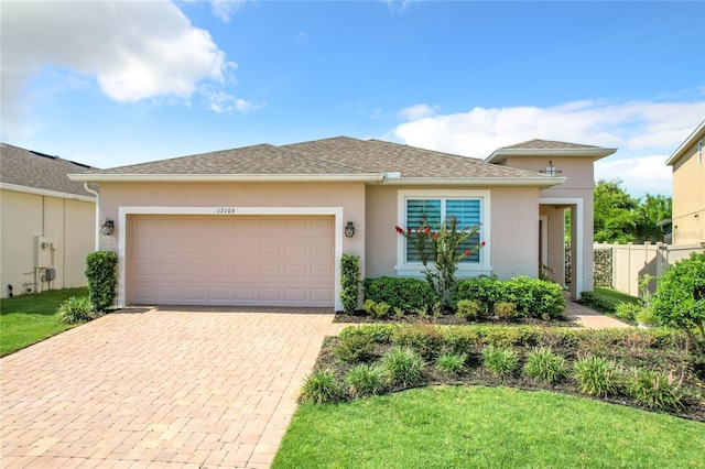 view of front of property featuring a garage, a shingled roof, fence, decorative driveway, and stucco siding