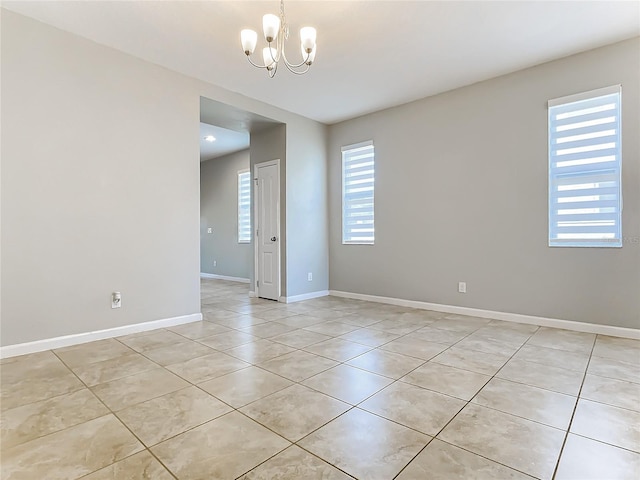 unfurnished room featuring light tile patterned floors, baseboards, and an inviting chandelier