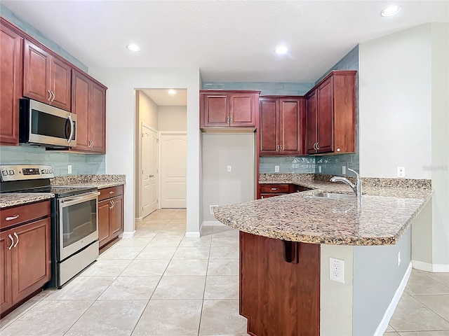 kitchen with light tile patterned floors, a kitchen breakfast bar, a peninsula, stainless steel appliances, and a sink