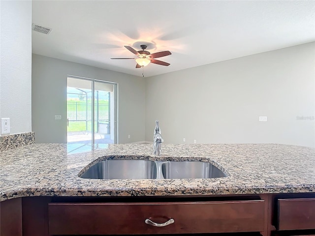 kitchen with a ceiling fan, visible vents, a sink, and light stone countertops