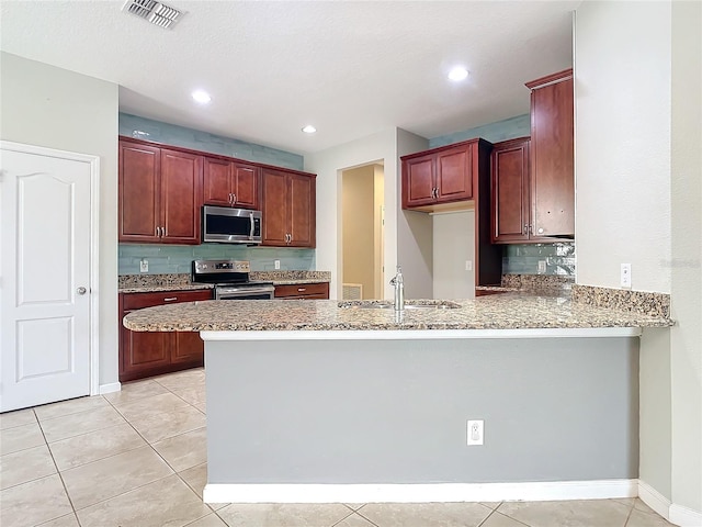 kitchen with a peninsula, visible vents, stainless steel appliances, and a sink