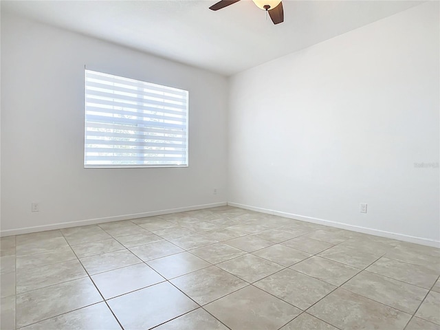 spare room with a ceiling fan and baseboards