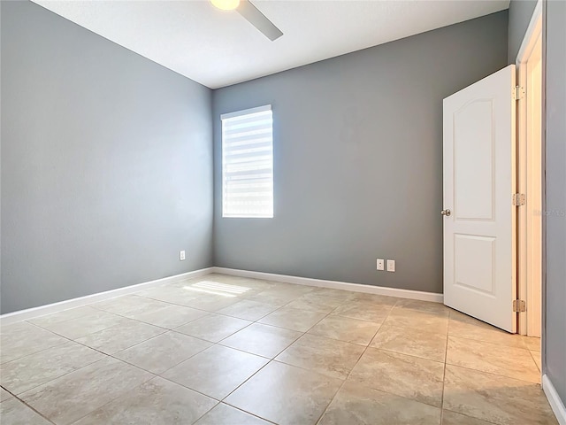 empty room with light tile patterned floors, baseboards, and a ceiling fan