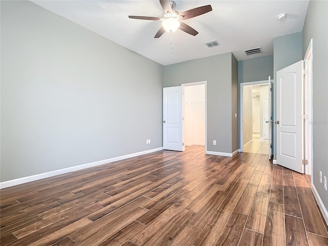 unfurnished bedroom with dark wood-type flooring, visible vents, and baseboards