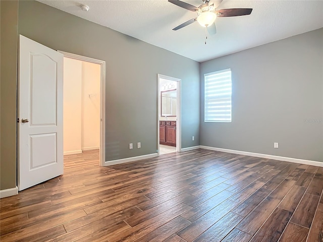 unfurnished bedroom featuring a textured ceiling, dark wood finished floors, a ceiling fan, baseboards, and ensuite bath