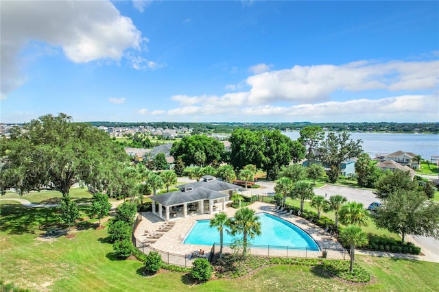 community pool featuring a patio area, a water view, fence, and a lawn