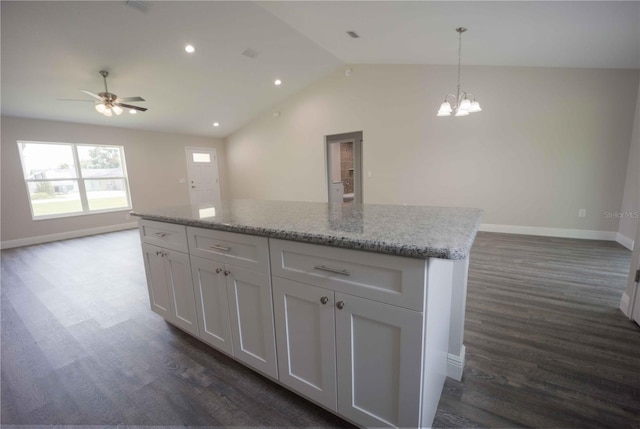 kitchen featuring white cabinets, dark hardwood / wood-style flooring, light stone countertops, hanging light fixtures, and vaulted ceiling