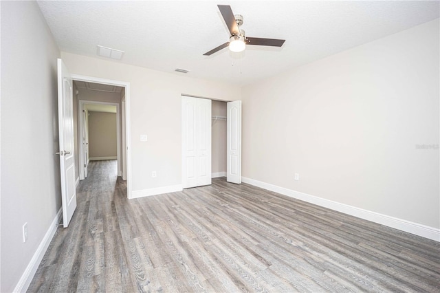 unfurnished bedroom featuring hardwood / wood-style flooring, ceiling fan, a textured ceiling, and a closet