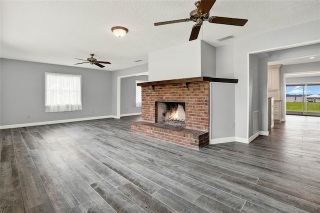 unfurnished living room with dark wood-type flooring, a textured ceiling, and a brick fireplace