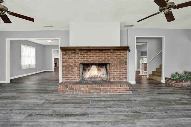 unfurnished living room featuring a fireplace, ceiling fan, dark hardwood / wood-style flooring, and a textured ceiling