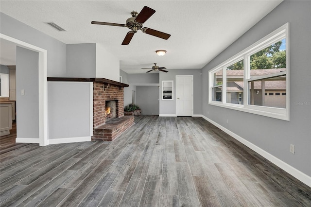 unfurnished living room featuring hardwood / wood-style flooring, a fireplace, ceiling fan, and a textured ceiling