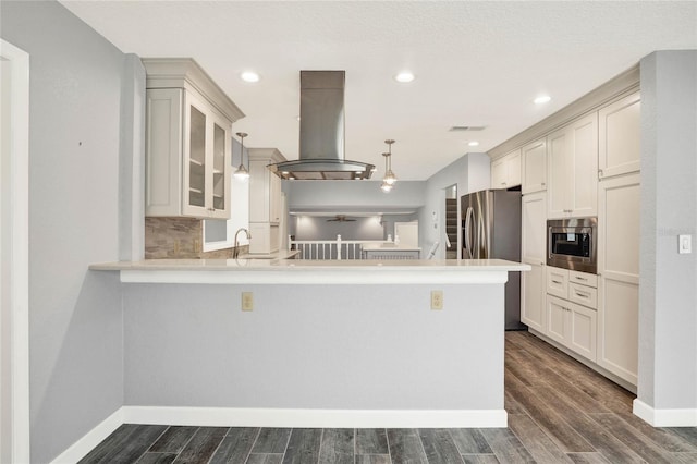 kitchen with island exhaust hood, kitchen peninsula, appliances with stainless steel finishes, decorative light fixtures, and dark hardwood / wood-style floors