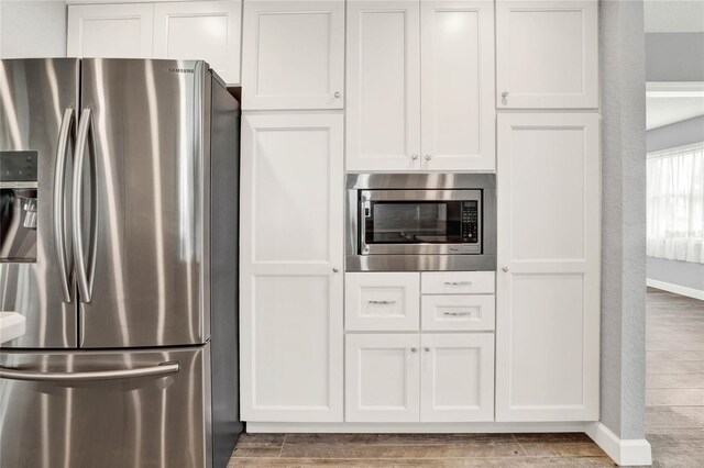 kitchen with white cabinets, appliances with stainless steel finishes, and dark hardwood / wood-style flooring