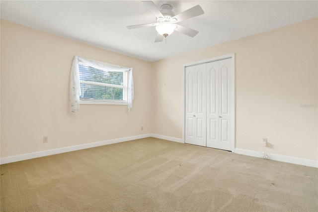 unfurnished bedroom featuring light carpet, a closet, and ceiling fan