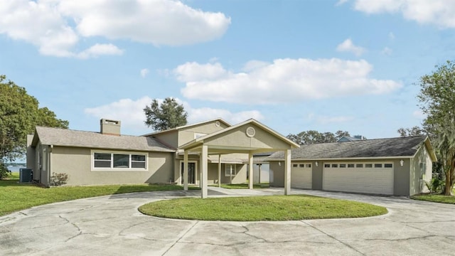 view of front facade featuring a front lawn, central AC unit, and a garage