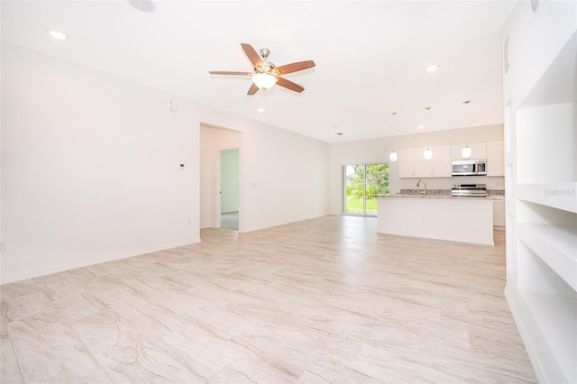 unfurnished living room featuring sink, light tile patterned floors, and ceiling fan