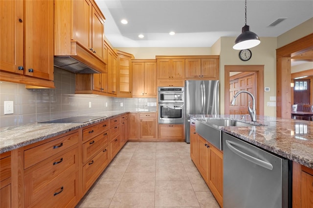 kitchen with sink, hanging light fixtures, light tile patterned floors, stainless steel appliances, and light stone countertops