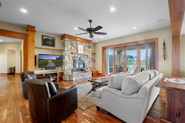 living room with ceiling fan, a fireplace, and hardwood / wood-style flooring