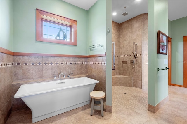 bathroom with shower with separate bathtub, tile patterned flooring, and tile walls