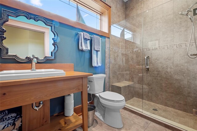 bathroom with tile patterned flooring, a shower with shower door, toilet, and sink