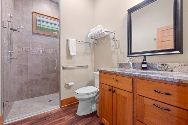 bathroom with vanity, a shower with shower door, toilet, and hardwood / wood-style floors