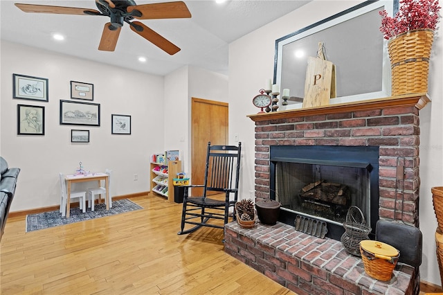 sitting room featuring a fireplace, light wood-type flooring, and ceiling fan