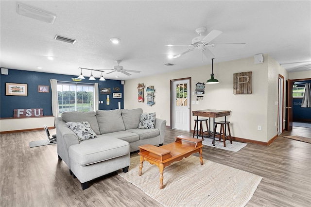 living room featuring a textured ceiling, wood-type flooring, ceiling fan, and rail lighting