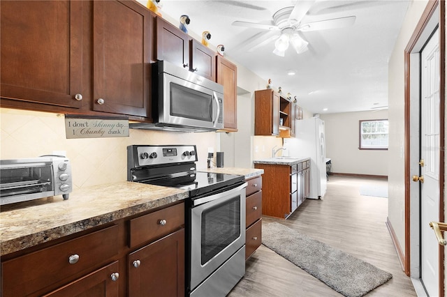 kitchen with light wood-type flooring, backsplash, ceiling fan, stainless steel appliances, and sink