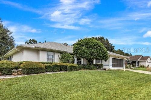 ranch-style home with a garage, a front lawn, concrete driveway, and stucco siding