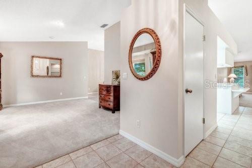 hall featuring light colored carpet, visible vents, baseboards, and light tile patterned floors