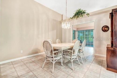 tiled dining room featuring vaulted ceiling and a chandelier