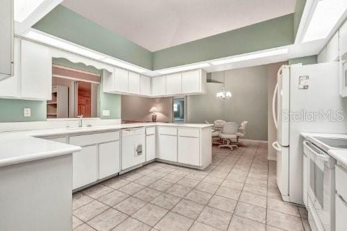 kitchen with white cabinets, stove, light tile patterned floors, and kitchen peninsula