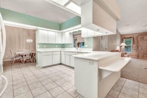 kitchen featuring an inviting chandelier, white cabinets, light tile patterned floors, and kitchen peninsula