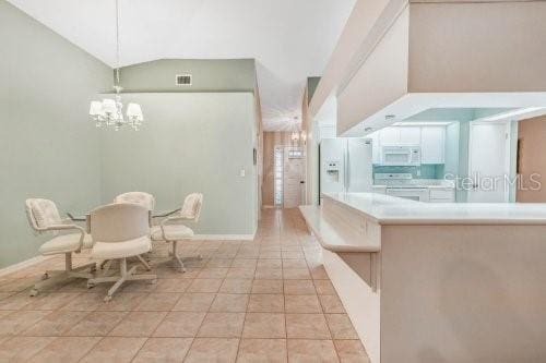 dining space featuring light tile patterned floors, vaulted ceiling, and a chandelier