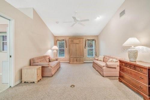 carpeted living room with ceiling fan and lofted ceiling