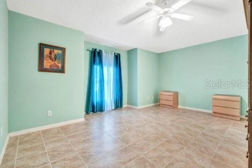 unfurnished room featuring light tile patterned flooring, a textured ceiling, and ceiling fan